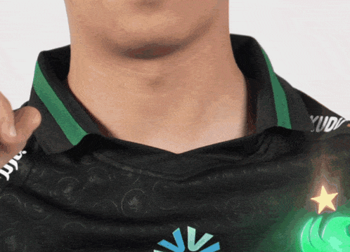 a man wearing a black shirt with a green star and a blue circle with the letter v on it