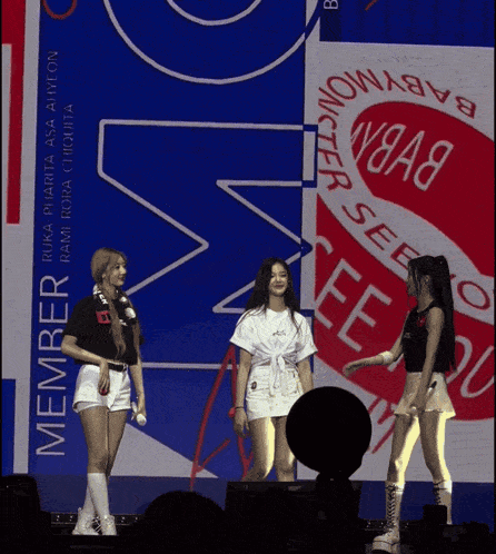 a group of girls standing on a stage in front of a sign that says member