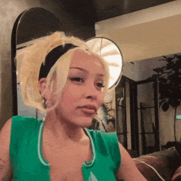 a woman with blonde hair and a green tank top has a tattoo on her chest that says " i love you "