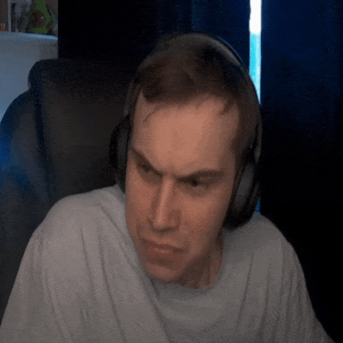 a man wearing headphones looks at the camera with a serious look on his face