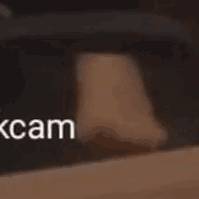 a close up of a person 's foot on a wooden table with the word cam in the corner .