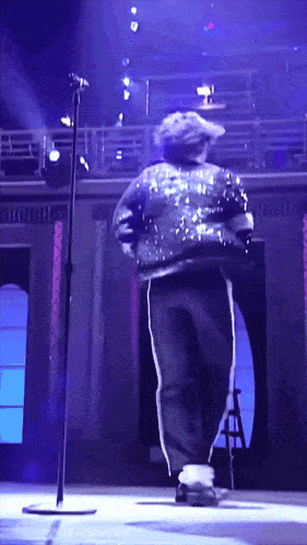 a man in a sequined jacket is dancing on stage
