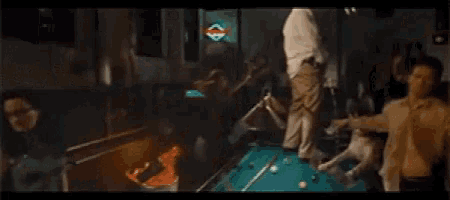 a man is standing on a pool table in front of a sign that says ' coca cola '
