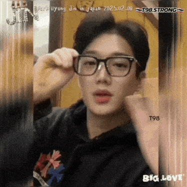 a picture of a young man wearing glasses and a t98 strong logo behind him