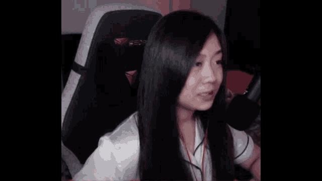 a woman with long hair is sitting in a chair with a microphone in front of her .