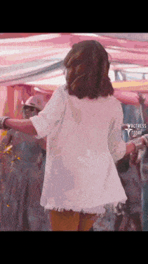 a woman in a white shirt is dancing in front of a crowd at a festival .