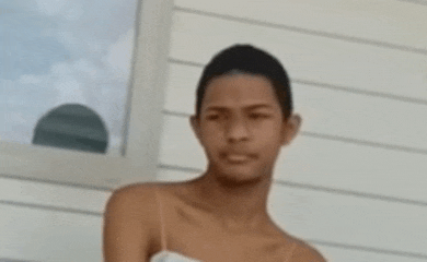 a young man wearing a white tank top is standing in front of a white wall .