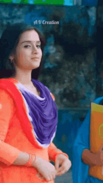 a woman in an orange and purple dress is standing next to a man in a blue shirt