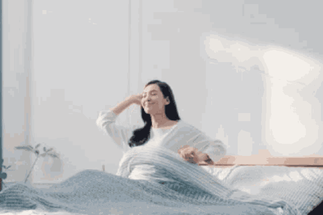 a woman is stretching her arms while laying on a bed