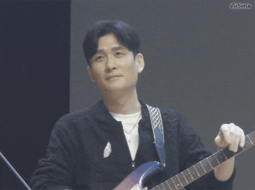 a man playing a guitar with victoria written on the bottom right