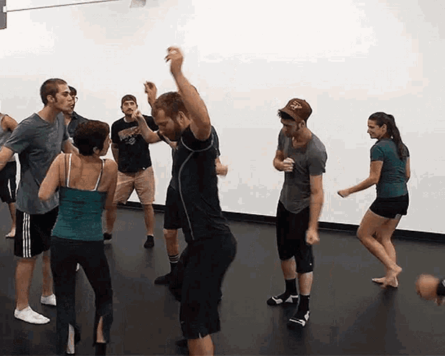 a group of people are dancing in a room with a man wearing a hat that says ' ucsd '