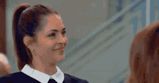 a close up of a woman wearing a blue scrub top making a funny face .