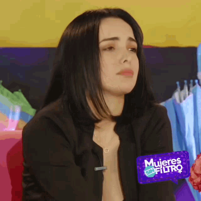 a woman sitting in front of a purple sign that says " mujeres filtro "