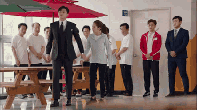 a man in a suit and tie holds a woman 's hand