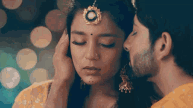 a man is kissing a woman on the forehead in a close up of their faces .