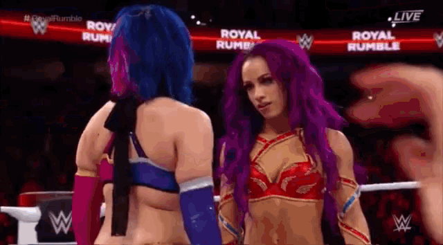 two women with purple hair are standing next to each other in a ring .
