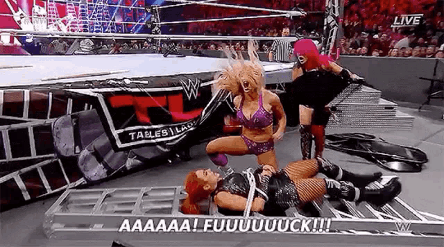 a woman in a purple bikini is laying on the ground in a wrestling ring while another woman screams .