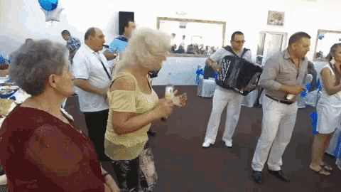 a group of people are dancing in a room and one man is playing an accordion