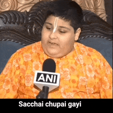 a boy wearing an orange shirt is talking into a microphone that says ani