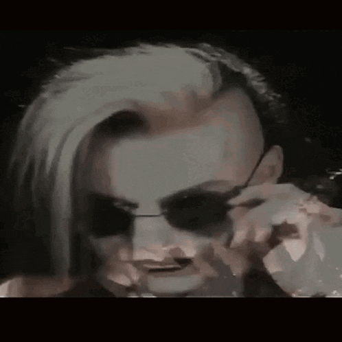 a woman with a shaved head and sunglasses on her face .