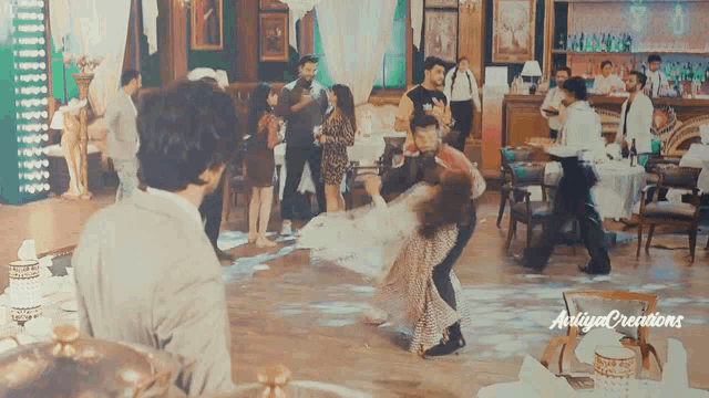 a group of people are dancing in a room with the word aniya creations on the bottom right