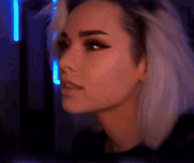 a close up of a woman 's face with a blue light in the background