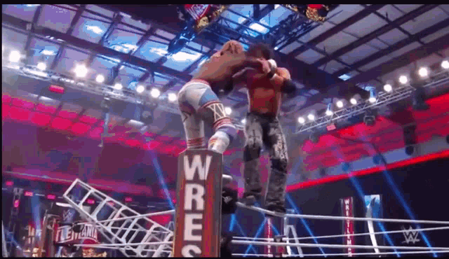 two men are wrestling in a ring with a sign that says wrestlemania on it .