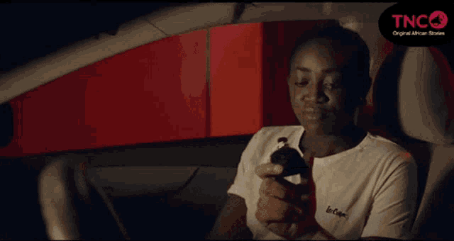 a woman is sitting in the driver 's seat of a car holding something in her hand .