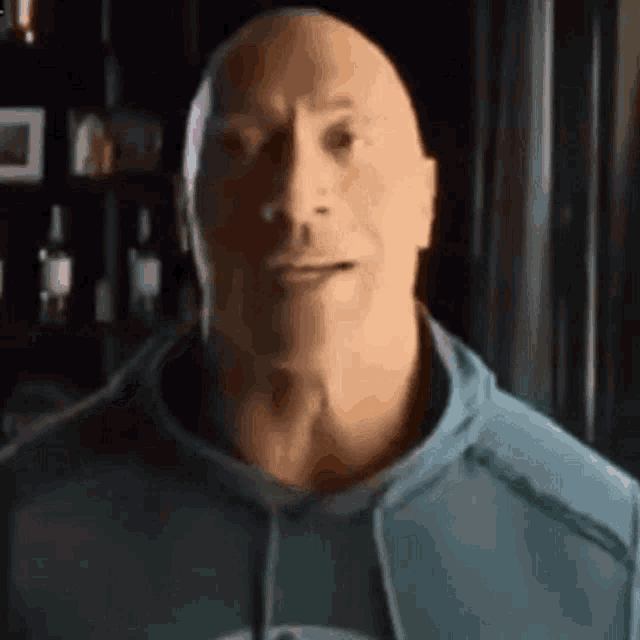 a close up of a bald man wearing a blue sweatshirt .