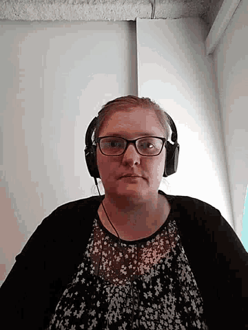 a woman wearing glasses and headphones is looking at the camera