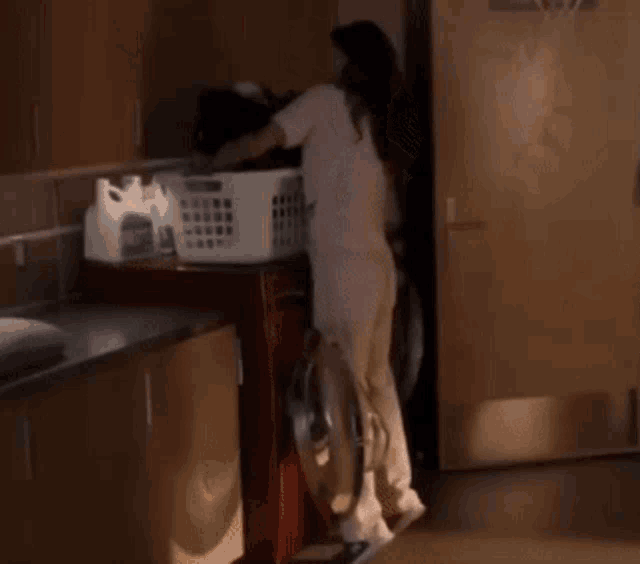 a woman is loading clothes into a washing machine
