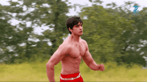 a man without a shirt is running in a field with the letter z behind him
