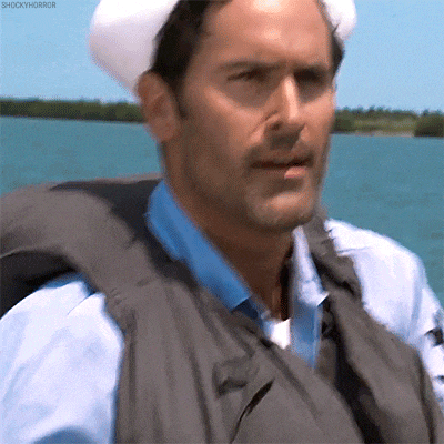 a man wearing a life vest and a sailor hat is looking at the camera .