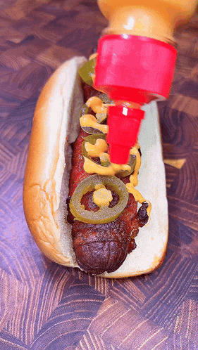 a hot dog with jalapenos and mustard is being poured on it