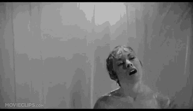a black and white photo of a woman taking a shower in a shower curtain .