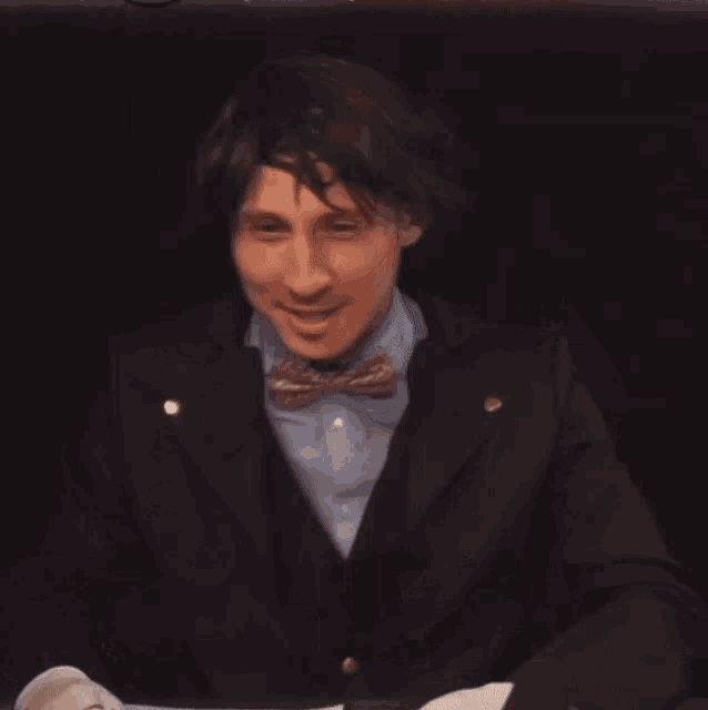 a man wearing a bow tie and white gloves is smiling