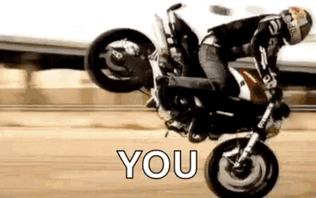 a man is doing a trick on a motorcycle on a road .