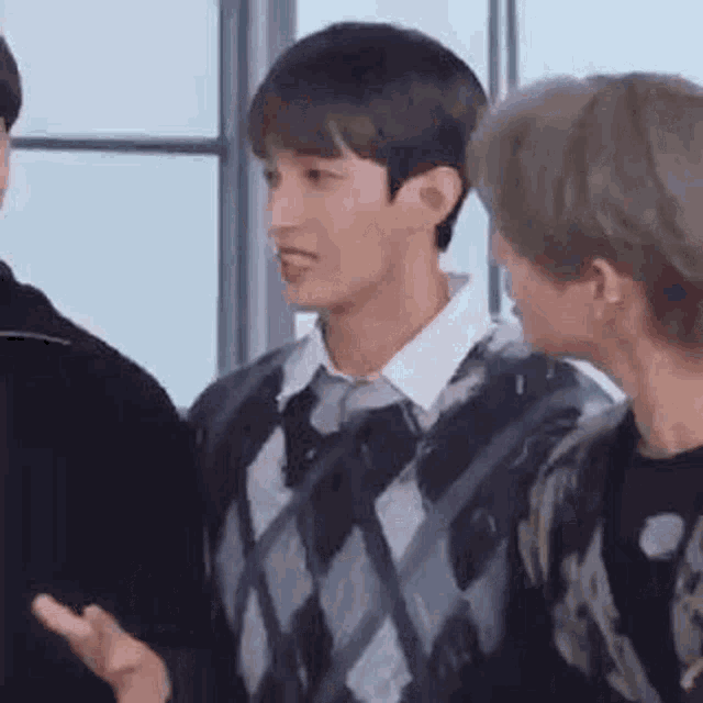 a group of young men are standing next to each other in a room and talking .
