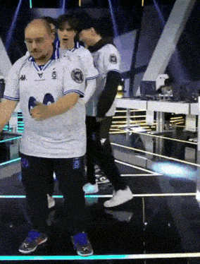 a man in a kappa shirt shakes hands with another man in a white shirt