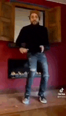 a man with a beard is dancing in a living room .