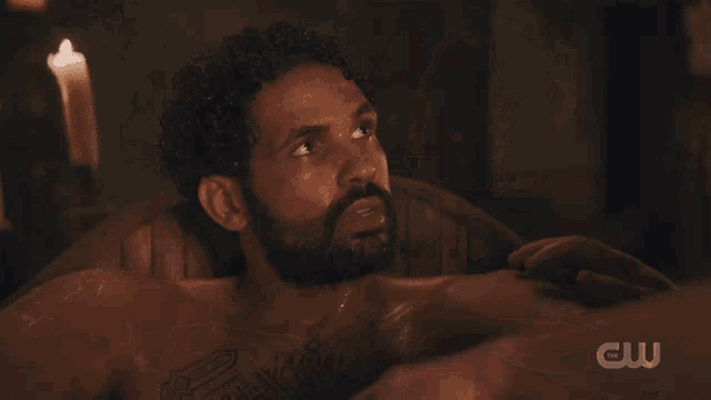 a man with curly hair and a beard is talking to another man with a cw logo in the corner