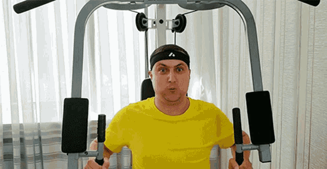 a man wearing a yellow shirt and a headband is using a machine .