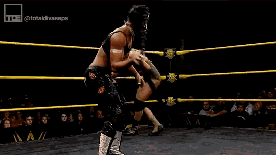 a man is wrestling another man in a ring with a crowd watching .