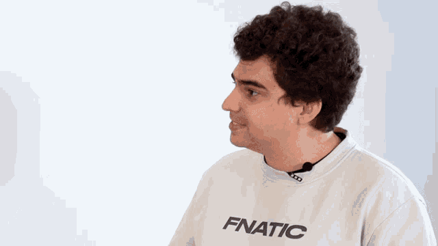 a man with curly hair wears a white fnatic sweatshirt