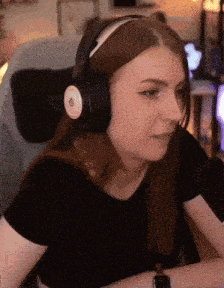 a woman wearing headphones is sitting in front of a microphone and looking at the camera .