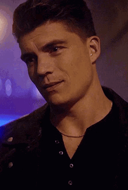 a close up of a man wearing a black shirt and a black jacket