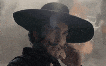 a man with a beard wearing a cowboy hat talking on a cell phone