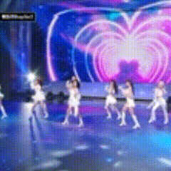 a group of women are dancing on a stage in front of a heart shaped screen