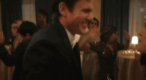 a man in a tuxedo is smiling at a woman in a dress