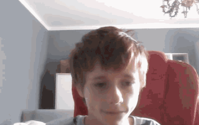 a young boy is sitting in a red chair in a living room